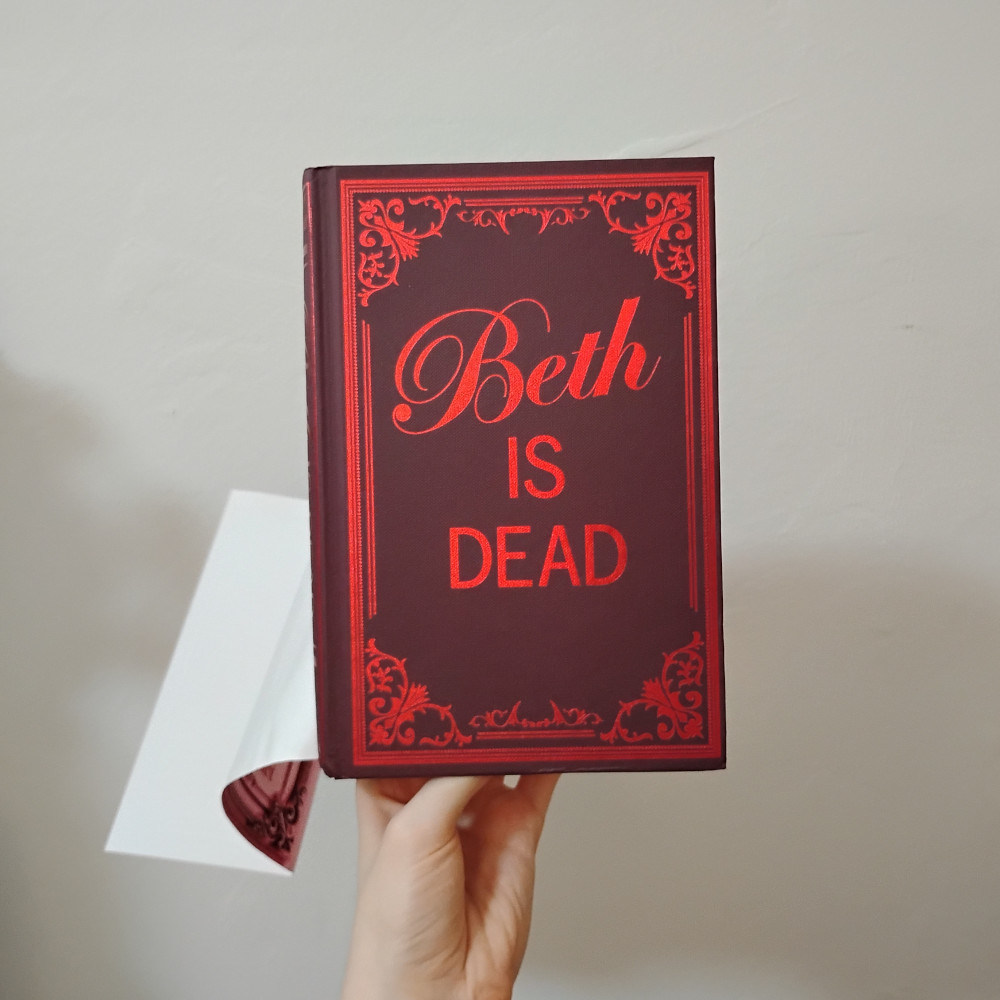 The book itself under the dust jacket is a dark purpleish color with the title in shiny red text.