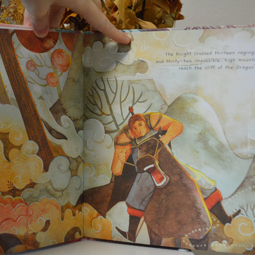 Photo of the inside of the books showing the knight riding his horse through a forest.
