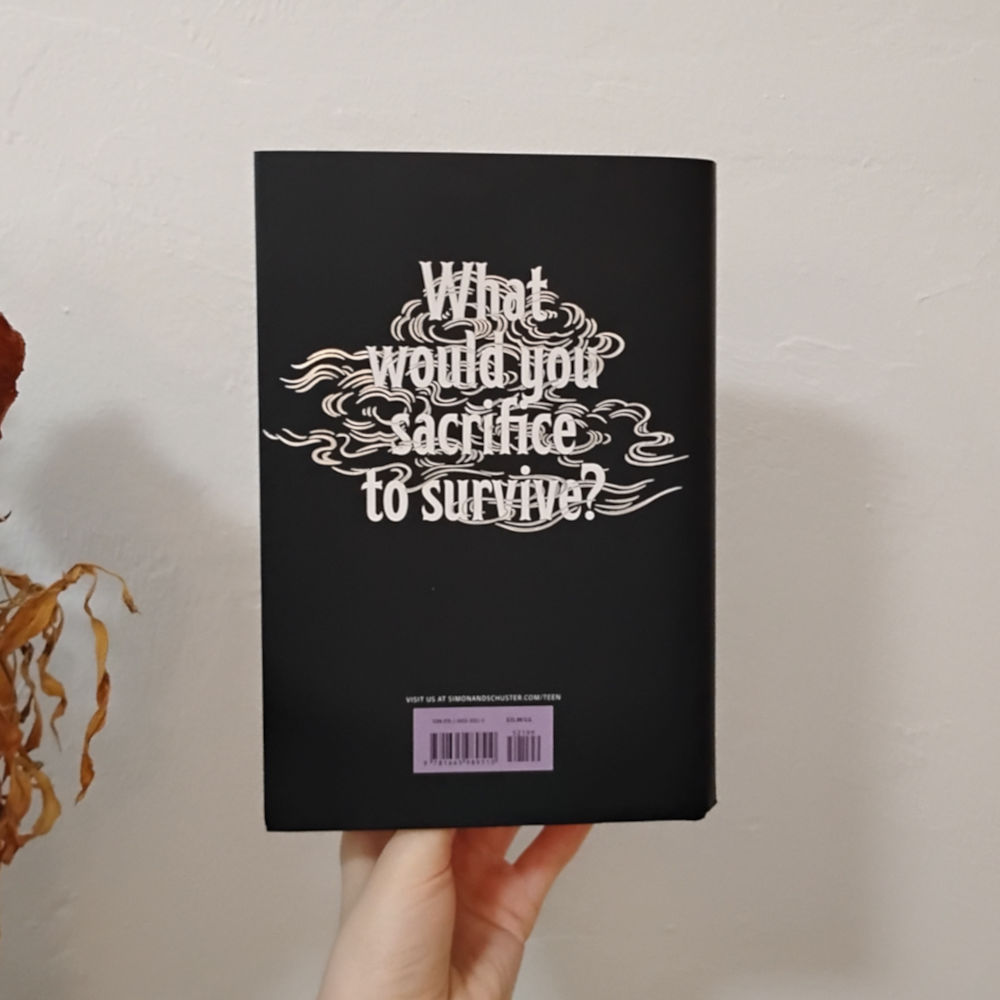 Photo of The Lure of Wolves and Whispers by Amanda Connolly back cover which has the same wind swirl but with big text that reads, 'What would you sacrifice to survive?'